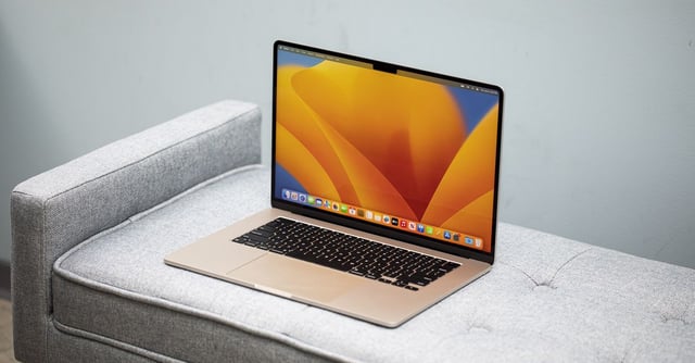 A Starlight MacBook Air 15-inch open on a gray couch.