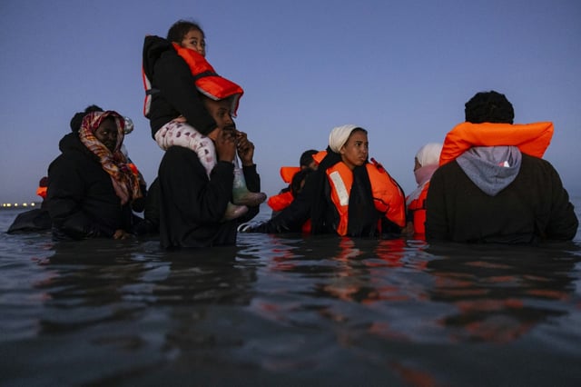 Des migrants avancent dans l'eau pour essayer de monter à bord d'un "bateau-taxi" pour traverser la Manche le 19 septembre 2025 au large de la plage de Gravelines, dans le nord de la France