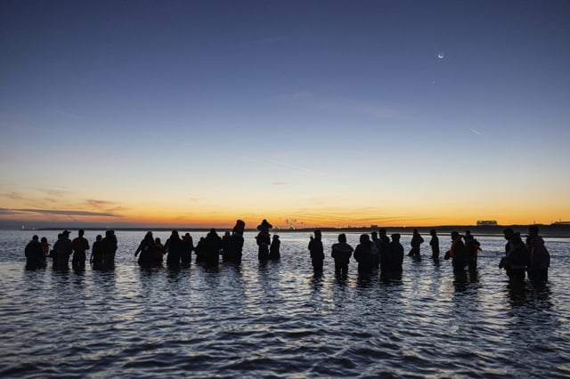 Des migrants avancent dans l'eau pour essayer de monter à bord d'un "bateau-taxi" pour traverser la Manche le 19 septembre 2025 au large de la plage de Gravelines, dans le nord de la France
