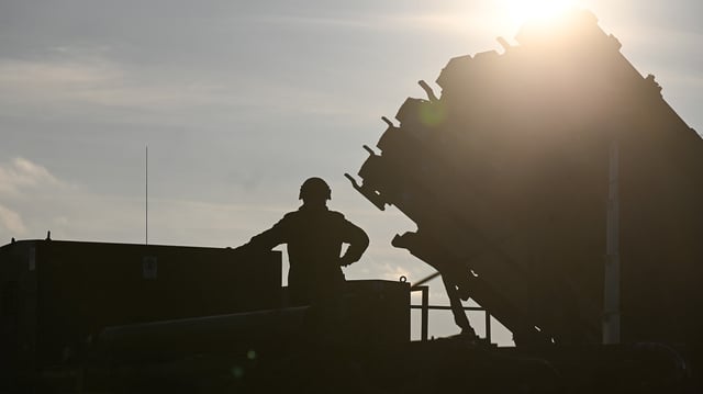 A German soldier stands on the top of a truck as he and others unload a Patriot surface-to-air missile system on January 23 in Poland.