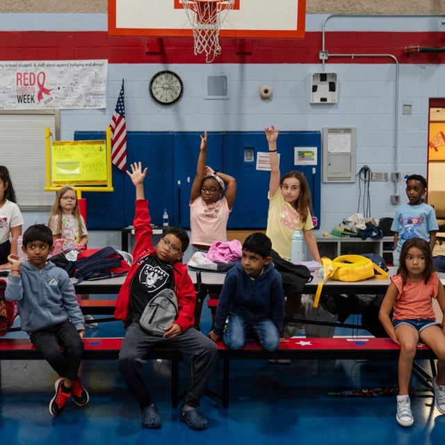 Children raise their hands while participating in activities during the East Providence Boys and Girls Club Summer Camp at Emma G. Whiteknact Elementary School on Thursday, July 10, 2025, in Providence R.I. (AP Photo/Sophie Park)
