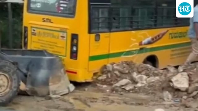 In the video released by PTI, a JCB machine is seen trying to push the bus out of the stormwater drain, while residents overlook the efforts.