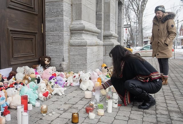 A woman lights a candle at a memorial outside a church close to the site of a daycare centre in Laval, Que, Thursday, February 9, 2023, where a bus crashed into the building killing two children. The man accused of murdering two children and injuring six others after a city bus crashed into Montreal-area daycare is scheduled to stand trial over five weeks beginning April 2025. THE CANADIAN PRESS/Graham Hughes