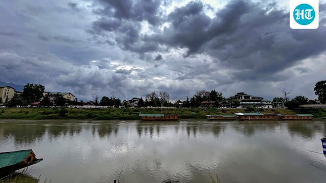 A man fishes in the Jhelum river as clouds cover the skyline, in Srinagar.