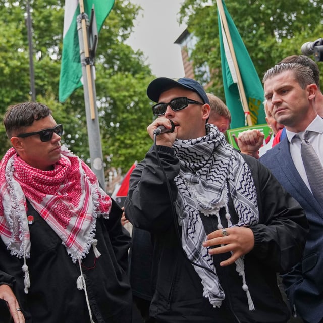 Liam Og O Hannaidh, second right, a member of Kneecap, speaks to supporters as he departs Westminster Magistrates Court in London on Aug. 20. In May, British police charged Og O Hannaidh with a terrorism offence for allegedly waving a Hezbollah flag at a 2024 concert. The rapper denied the offence.