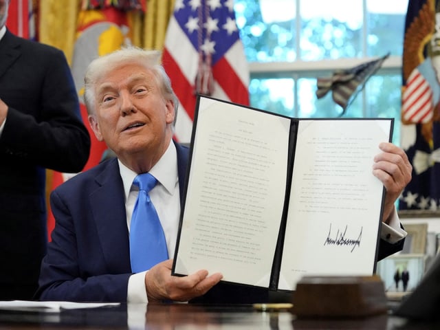 U.S. President Donald Trump displays a signed executive order on gold card visa in the Oval Office at the White House in Washington, D.C., U.S., September 19, 2025. REUTERS/Ken Cedeno