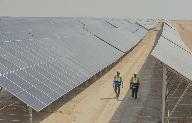 Workers walk between solar panels at a newly opened industrial-scale solar power plant in Karbala, Iraq, Wednesday, Sept. 17, 2025. (AP Photo/Anmar Khalil)