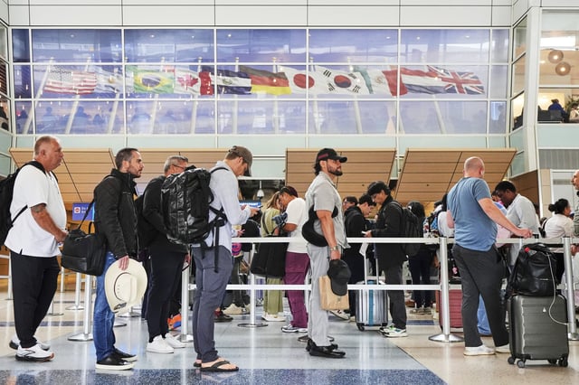 Travelers stand in line at a security checkpoint before boarding their international flights at Dallas Fort Worth International Airport, Friday, Aug. 29, 2025, in DFW Airport, Texas.
