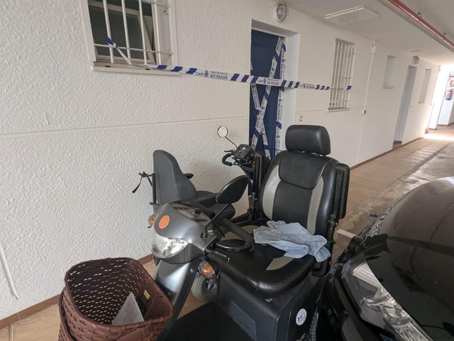 Silla eléctrica de la mujer estrangulada en Benidorm por una amiga. Detrás, su vivienda precintada.