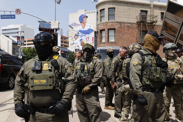 Masked U.S. Border Patrol agents produce a show of force outside the Japanese American National Museum in Los Angeles while California Gov. Gavin Newsom holds a redistricting news conference in August. A law signed by Newsom on Saturday bans federal officers from wearing masks to conceal their identities starting Jan. 1.