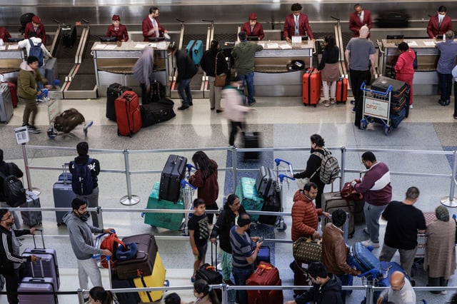 Travelers wait in line at the check-in counter at the Dallas-Fort Worth International Airport on Dec. 12, 2023.