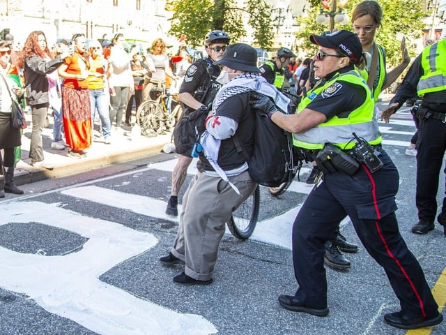  Protesters clashed with Ottawa police multiple times on Wellington Street as officers attempted to clear the roadway and stop demonstrators from painting, eventually seizing jugs of paint after several altercations.