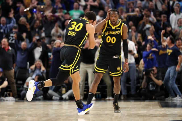 Jonathan Kuminga #00 watches Stephen Curry #30 of the Golden State Warriors do his "Night Night" celebration during their game against the Boston Celtics at Chase Center on December 19, 2023 in San Francisco, California.
