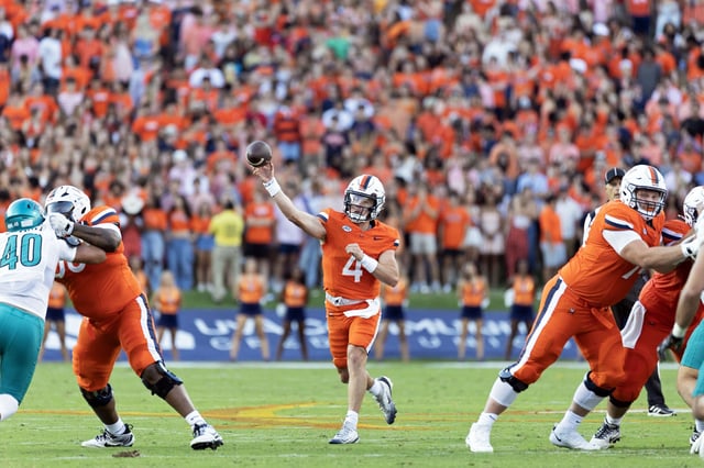 Chandler Morris #4 throws a pass from between Tyshawn Wyatt #56 and Ethan Sipe #74 of the Virginia Cavaliers in the first half during a game against the Coastal Carolina Chanticleers at Scott Stadium on August 30, 2025 in Charlottesville, Virginia.