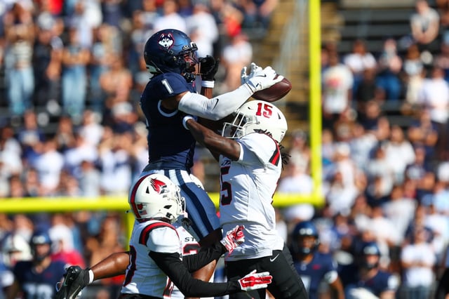 UConn wide receiver Skyler Bell uses Ball State defender DJ Field's helmet to gain control of a first-half reception during Saturday's game at Rentschler Field.  (Brian Foley/Clarus Media)