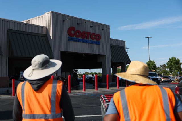 Employees push shopping carts outside a Costco Wholesale warehouse store in Hawthorne, California, on August 27.