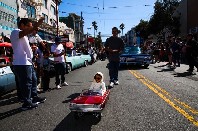 Cesar Rios of Modesto remote-controls a 1964 Chevrolet Impala carrying his 2-year-old son, Cesar Rios Jr., during the lowrider parade. 