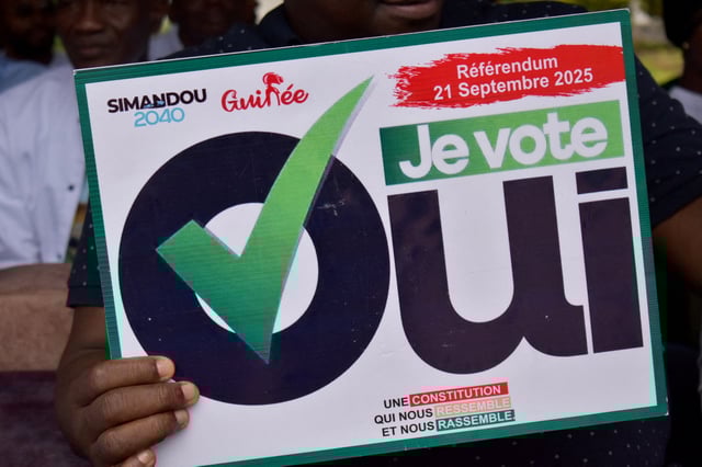 A citizen holds a sign as they take part in a rally during the awareness campaign for the upcoming September 21 referendum on a new constitution, in Conakry, Guinea September 16, 2025. The sign reads "I vote yes". REUTERS/Souleymane Camara/File Photo