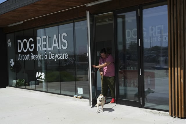 A costumer walks with her dog as she leaves the Dog Relais, a hotel for dogs at Rome's Fiumicino International Airport, Wednesday, Sept. 17, 2025. (AP Photo/Alessandra Tarantino)