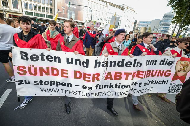 Mehrere junge Männer halten ein Transparent in die Höhe, auf dem steht: "Beten und handeln, um die Sünde der Abtreibung zu stoppen"