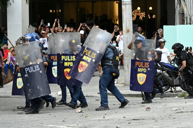 Des policiers se protègent de jets de pierre lors d'une manifestation à Manille le 21 septembre 2025