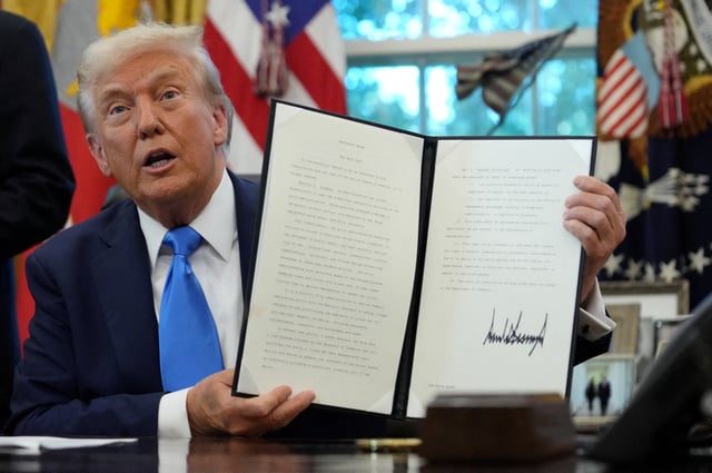 U.S. President Donald Trump displays a signed executive order on gold card visa in the Oval Office at the White House in Washington, D.C., U.S., September 19, 2025. REUTERS/Ken Cedeno/File Photo