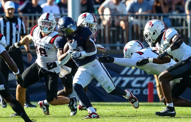 UConn running back Cam Edwards, center, clutches the ball as he works his way through the Ball State defense Saturday.  (Brian Foley/Clarus Media)
