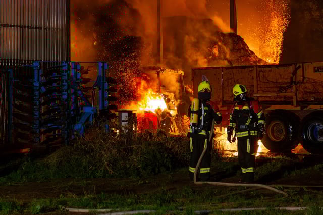 Einsatzkräfte vor der brennenden Lagerhalle.
