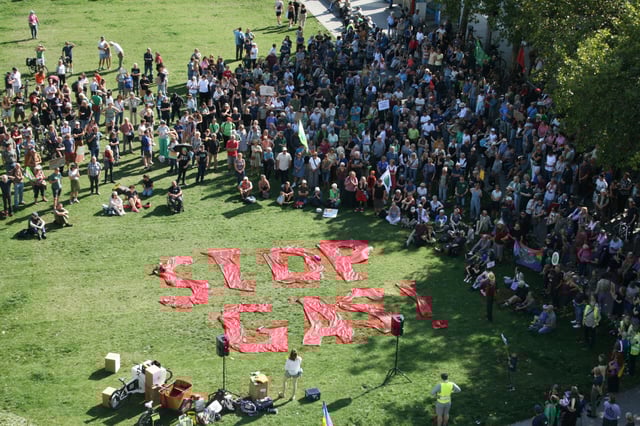 Teilnehmer stehen während einer Demonstration von Fridays for Future auf einer Wiese vor dem Überseemuseum neben einem Slogan „Stop Gas!”.