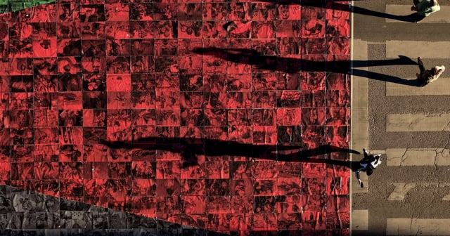 People walk next to a Palestinian flag made of photographs of dead civilians, displayed on a street in Sarajevo, Bosnia. AP Photo