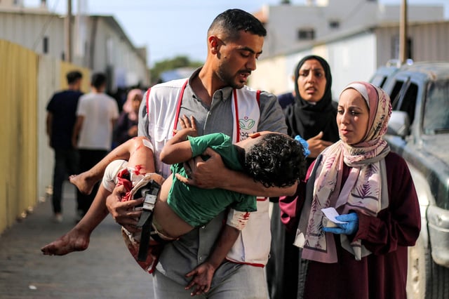 Un trabajador del Hospital al-Awda carga a un niño herido por un presunto bombardeo israelí contra al-Bureij, en las afueras del hospital en Nuseirat, en el centro de la Franja de Gaza, el 21 de septiembre de 2025