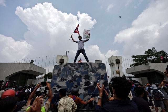 A demonstrator waves a flag as he stands atop a vehicle near the entrance of the Parliament during a protest against corruption and government’s decision to block several social media platforms, in Kathmandu, Nepal September 8, 2025. REUTERS/Navesh Chitrakar/File Photo