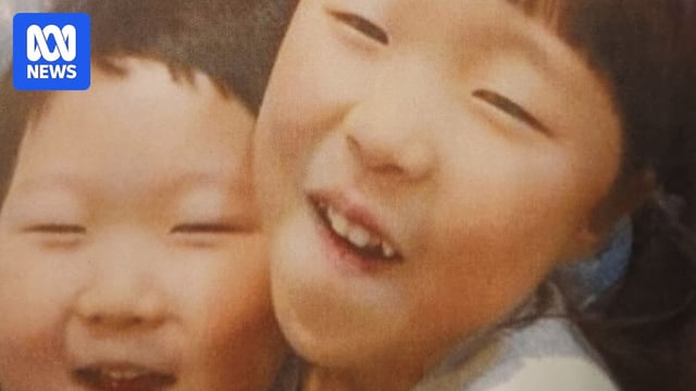 a korean family with two parents and two young children crowd into a camera for a selfie 