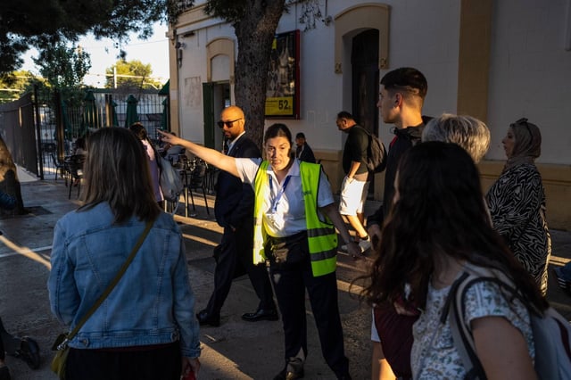 Una informadora señala a los viajeros el camino a los buses desde la estación de Sitges, este lunes.