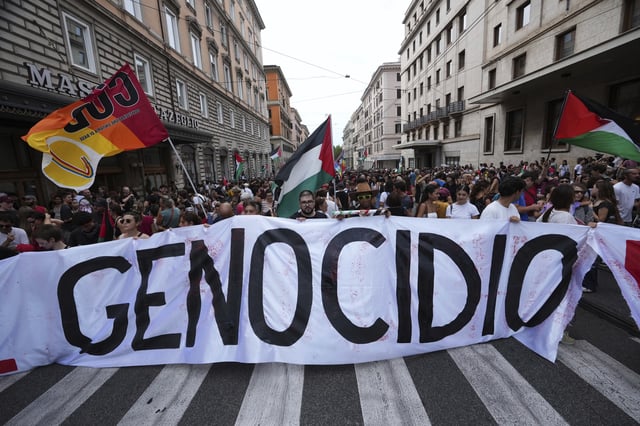 People hold a banner reading "genocide" as they participate at a demonstration part of a nation-wide protest and general strike against the war in Gaza, in Rome, Monday, Sept. 22, 2025. (AP Photo/Alessandra Tarantino)