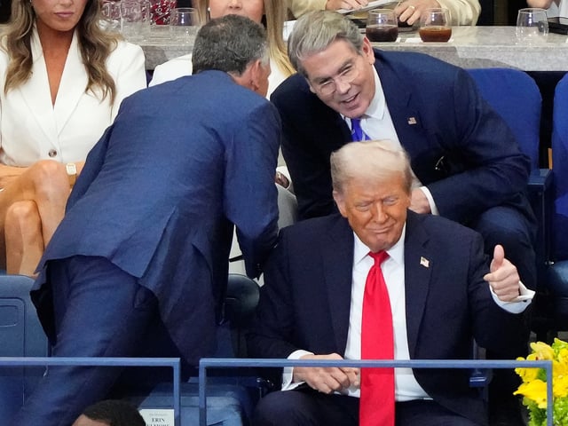 President Donald Trump motions to spectators as Secretary of Treasury, Scott Bessent, and Steve Witkoff talk during the men's singles final of the U.S. Open tennis championships, Sunday, Sept. 7, 2025, in New York. (AP Photo/Yuki Iwamura)