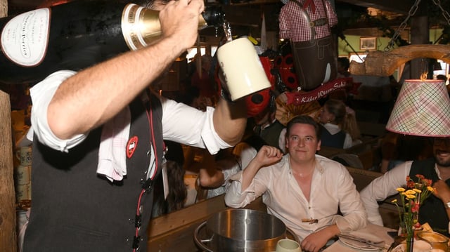 Ein Wiesn-Kellner gießt Schampus in einen Krug