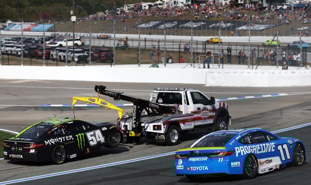 Ty Gibbs, driver of the #54 Monster Energy Toyota, is towed after an on-track incident as Denny Hamlin, driver of the #11 Progressive Toyota, drives during the NASCAR Cup Series Mobil 1 301 at New Hampshire Motor Speedway on September 21, 2025 in Loudon, New Hampshire.