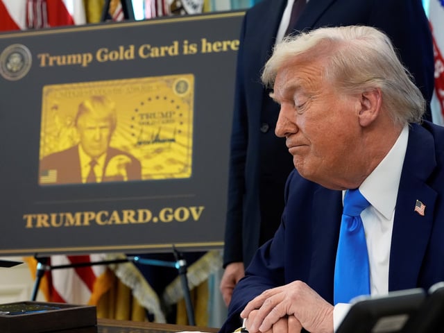A poster showing the Trump Gold Card is seen as President Donald Trump signs executive orders in the Oval Office of the White House, Friday, Sept. 19, 2025, in Washington. (AP Photo/Alex Brandon)