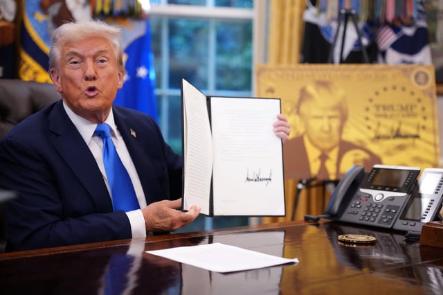 President Donald Trump holds up an executive order establishing the "Trump Gold Card" in the Oval Office at the White House on September 19, 2025.
