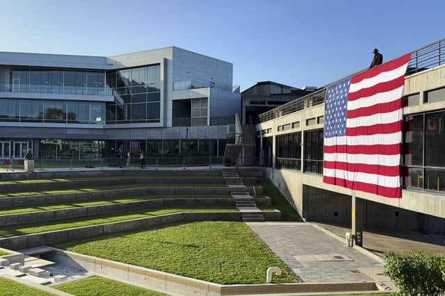 FILE - A national flag hangs over the site where conservative activist Charlie Kirk was shot and killed, at Utah Valley University, on Sept. 17, 2025, in Orem, Utah. (AP Photo/Jesse Bedayn, File)