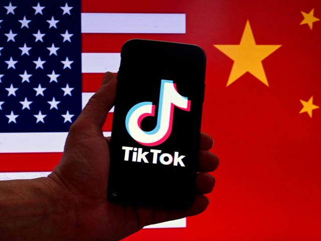 (FILES) In this photo illustration the social media application logo for TikTok is displayed on the screen of an iPhone in front of a US flag and Chinese flag background in Washington, DC, on March 16, 2023. The US Senate on Tuesday approved legislation requiring the wildly popular social media app TikTok to be divested from its Chinese parent company ByteDance or be shut out of the American market. The measure was part of a $95 billion foreign aid package, including military assistance to Ukraine, Israel and Taiwan, which has now cleared Congress and heads to President Joe Biden's desk. (Photo by OLIVIER DOULIERY / AFP)