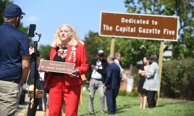Andrea Chamblee, whose husband John McNamara was one of the five victims of the 2018 shooting at the Capital Gazette, holds a highway marker while speaking with a journalist following a highway sign dedication marking a one-mile section of Rowe Blvd. in Annapolis for The Capital Gazette Five, on Monday. (Brian Krista/Staff)