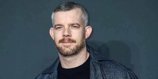 Russell Tovey with a slight smile on the red carpet for an event