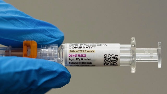 FILE - A pharmacist holds a Pfizer and BioNTech COVID-19 vaccine shot on Thursday, April 24, 2025, in Portland, Ore. (AP Photo/Jenny Kane, File)