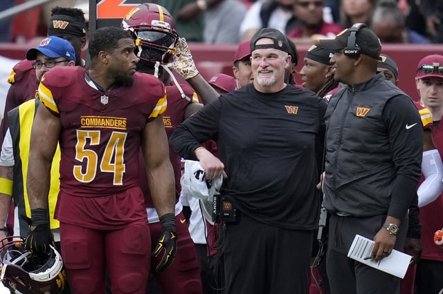 Bobby Wagner #54 of the Washington Commanders checks on Head coach Dan Quinn of the Washington Commanders after he hurt his nose during the second quarter against the Las Vegas Raiders at Northwest Stadium on September 21, 2025 in Landover, Maryland.