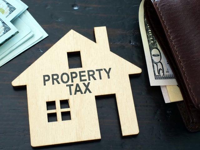 A property tax sign is shown on a house model.