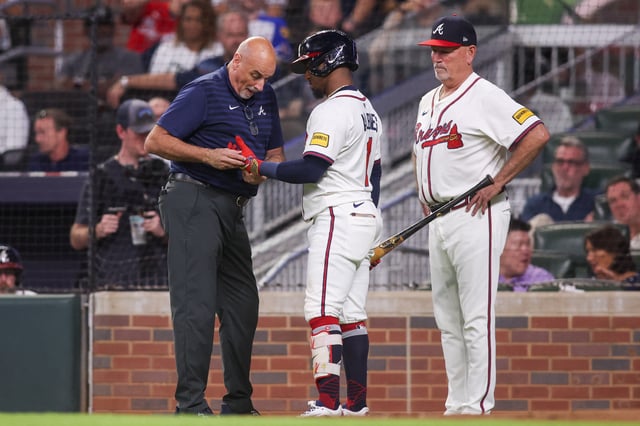 Sep 22, 2025; Atlanta, Georgia, USA; Atlanta Braves trainer George Poulis works on second baseman Ozzie Albies (1) against the Washington Nationals in the third inning at Truist Park. Mandatory Credit: Brett Davis-Imagn Images