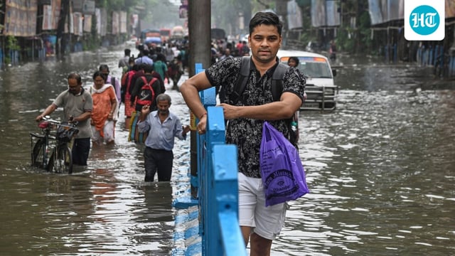 People make their way through a flooded road after heavy rainfall, in Kolkata on Tuesday, September 23