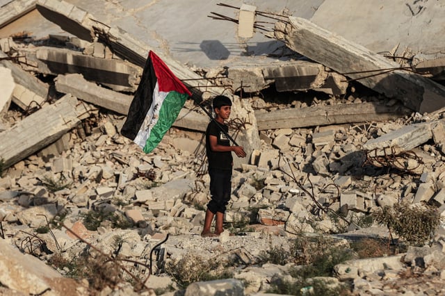 Group of Palestinian children in Bureyc Camp raise the Palestinian flag over the rubble of buildings destroyed by Israeli strikes following announcements of recognition of the State of Palestine by Canada, Australia, the UK, and Portugal, on September 22, 2025, in Gaza City, Gaza.